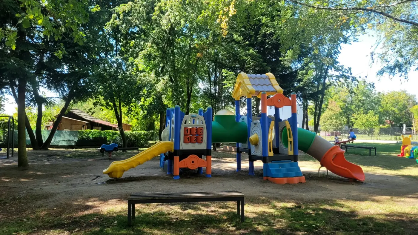 Duży plac zabaw ze zjeżdżalniami wśród drzew